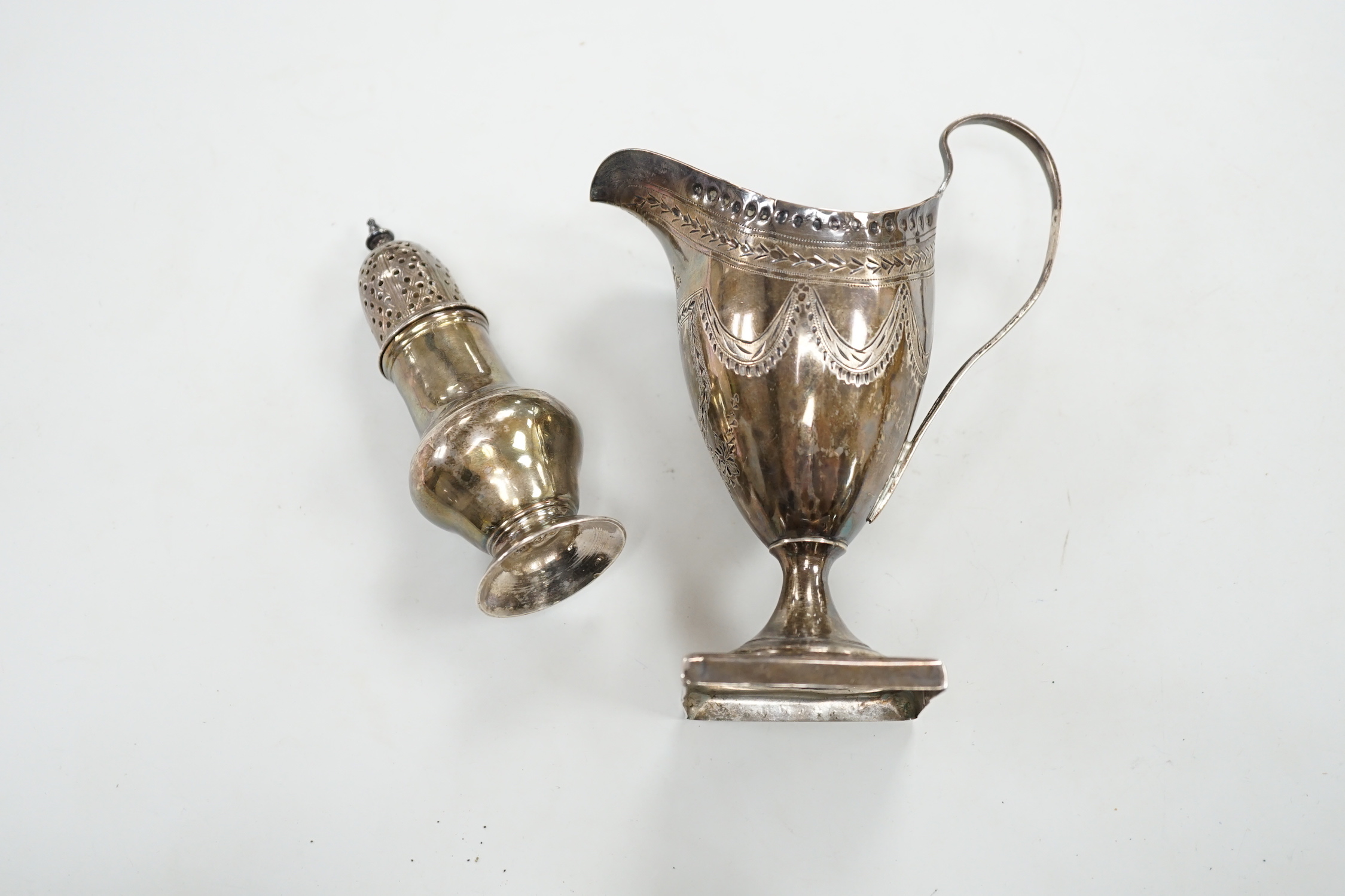 A George III silver helmet shaped cream jug, on square base, London, 1791 (overstruck maker's mark), 14.3 cm(a.f.) and a George II silver pepperette, London, 1755, (a.f.), 5.4oz.